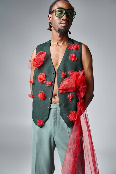 handsome african american man in trendy vest with red tulle fabric looking away, fashion concept - Photo, Image