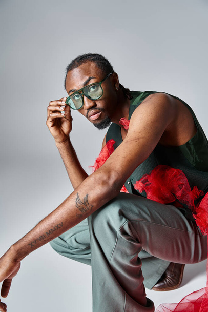 attractive african american man stylish outfit squatting on gray backdrop, fashion concept - Φωτογραφία, εικόνα
