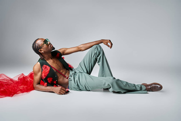見栄えの良いアフリカ系アメリカ人男性は,床にリクライニング赤いチュール生地のトレンディな服装 - 写真・画像