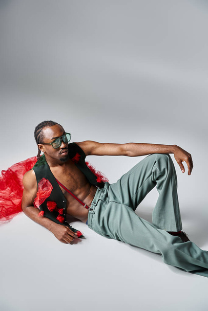 bell'uomo afro-americano dall'aspetto elegante in abito alla moda con tessuto di tulle rosso disteso sul pavimento - Foto, immagini
