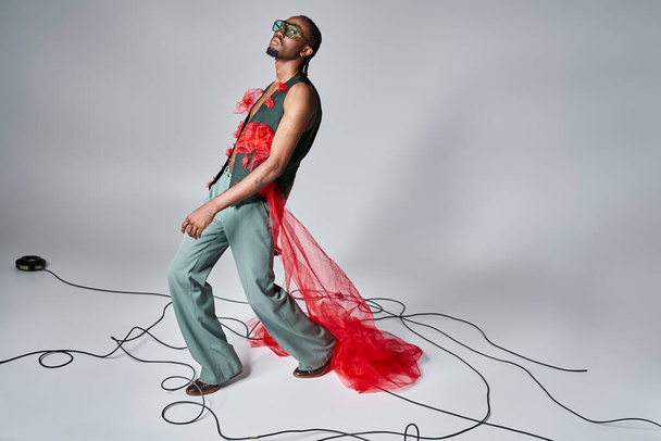 hombre afroamericano de moda con gafas de sol de moda posando en movimiento y mirando a la cámara - Foto, imagen