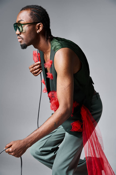 fashionable african american male model with red tulle fabric posing in motion and looking away - Fotó, kép