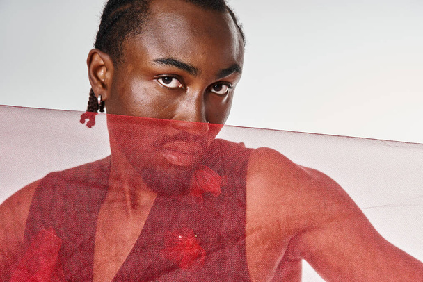 Gri arka planda canlı kırmızı tül kumaşla poz veren genç Afro-Amerikan erkek modeller. - Fotoğraf, Görsel