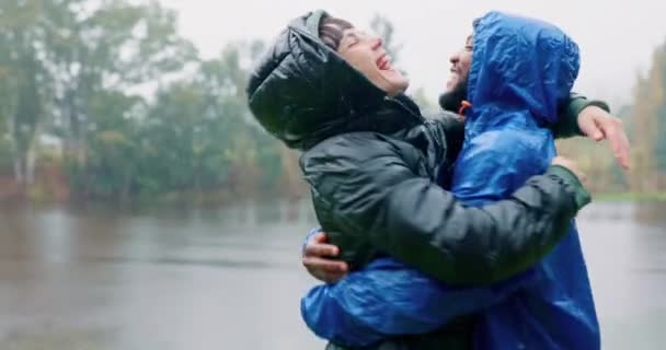 Hiking, love and an interracial couple hugging in the rain while outdoor in nature together for romance or adventure. Smile, freedom or travel with a man and woman camping in wet winter weather. - Footage, Video