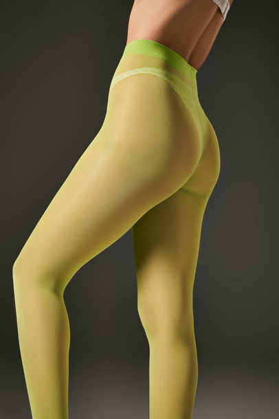 rajattu kuva nuoresta naisesta vihreissä sukkahousuissa poseeraa harmaalla taustalla, sukat käsite - Valokuva, kuva