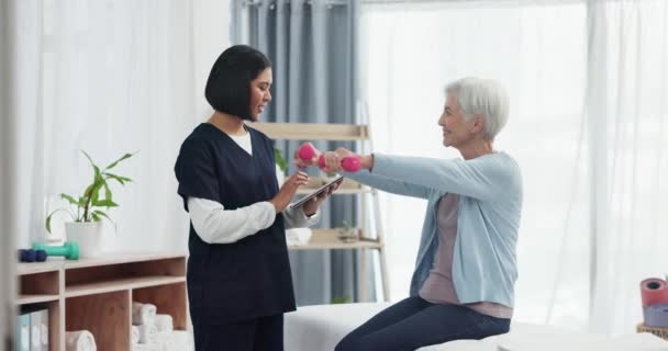 Senior woman, physical therapy and weights for injury and arm muscle check for health. Physiotherapy, elderly female patient and sport doctor with consultation and tablet for support and care. - Footage, Video