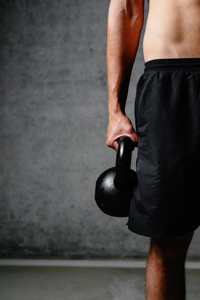 Muscular arm holding a kettlebell - Photo, image