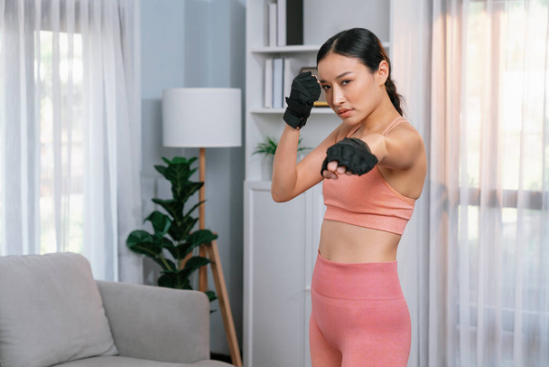 Fit young asian woman portrait in sportswear preparing herself before healthy exercising routine at home. Domestic fitness workout training on living room. Vigorous - Photo, Image
