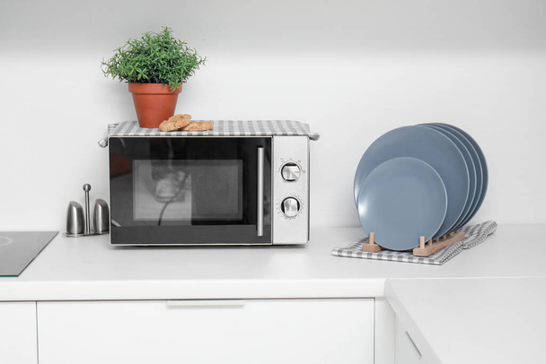 Modern mikrohullámú sütő háztartási és tányértartó fehér konyhapulton - Fotó, kép
