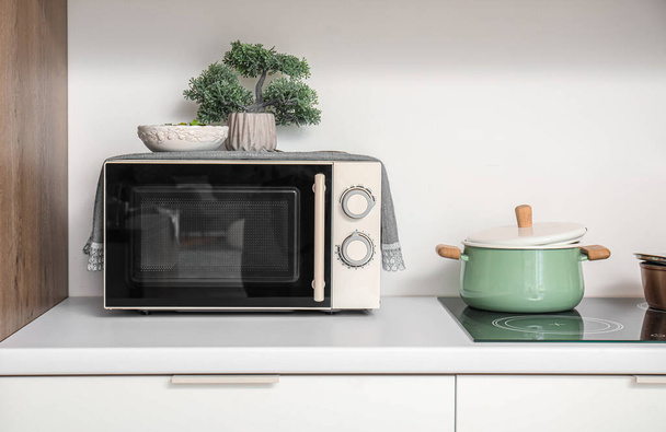 Modern mikrohullámú sütő és főzőedény fehér konyhapulton - Fotó, kép
