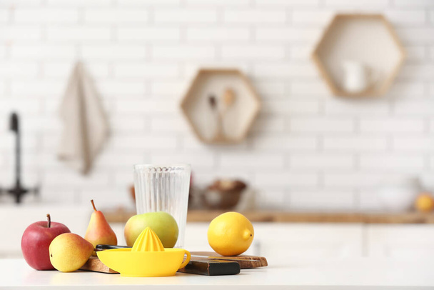 Ripe fruits and juice squeezer on table in kitchen - Photo, Image
