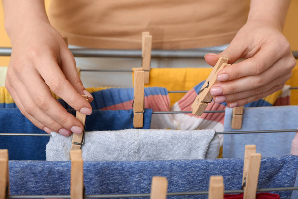 Женщина вешает чистую детскую одежду на сушилку, крупным планом - Фото, изображение