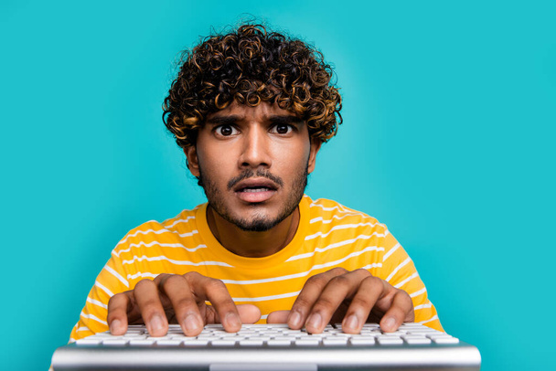 Фото безмовної враженої людини, яка дивиться пальці, друкуючи записує клавіатуру ізольовано на фоні кольору сліз. - Фото, зображення