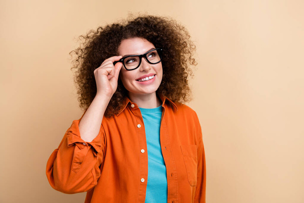 Photo portrait of lovely young lady touch eyeglasses look empty space dressed stylish orange garment isolated on beige color background. - Photo, image