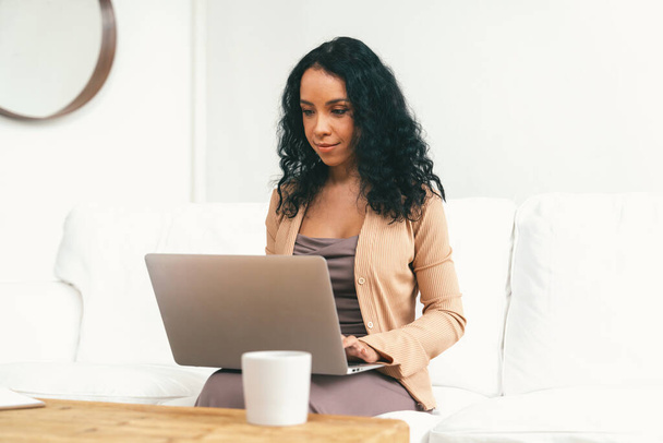 Mujer afroamericana que usa computadora portátil para un trabajo crucial en Internet. Secretaria o redacción de contenido en línea trabajando en casa. - Foto, Imagen