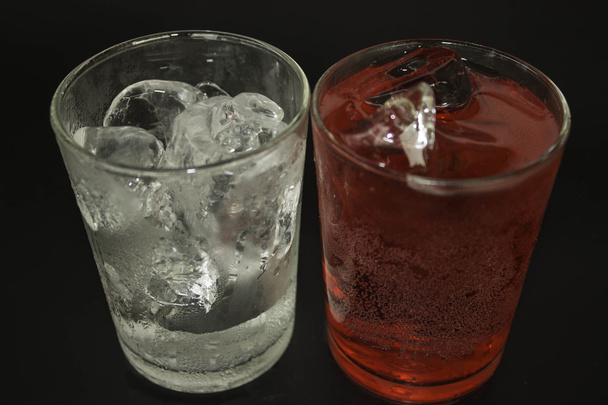 Water in a glass of red on a black background. - Photo, Image