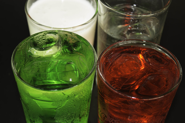 Piros és a zöld és a jégkocka egy pohár, egy fekete háttér. - Fotó, kép