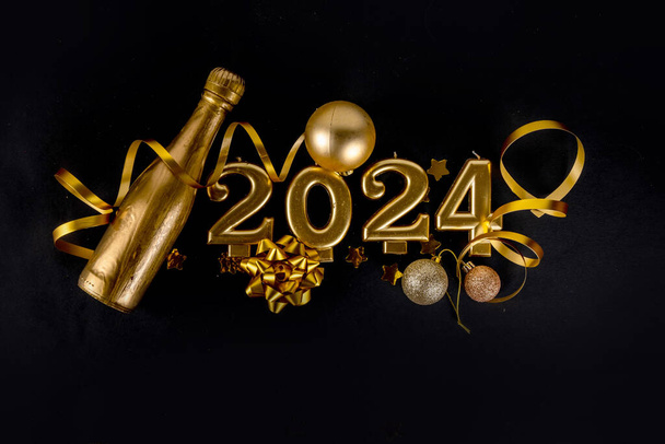 Поздравительные открытки 2024 года фон с золотыми номерами, бутылка шампанского, змея, рождественские и новогодние украшения на черном фоне копировального пространства - Фото, изображение