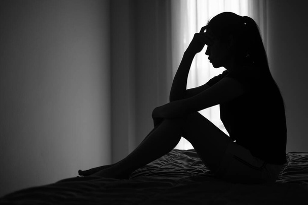 Σιλουέτα καταθλιπτικής γυναίκας που κάθεται στο υπνοδωμάτιο δίπλα σε προβλήματα υγείας συσσωρευμένο άγχος Προβλήματα σχέσης. - Φωτογραφία, εικόνα