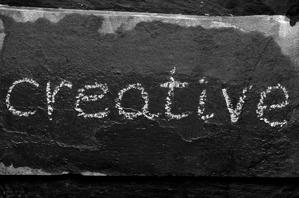 The word CREATIVE written with chalk on black stone. - Zdjęcie, obraz