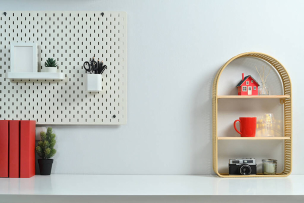 Lugar de trabajo sencillo con libros, cámara, modelo de casa, taza de café y pizarra en la pared blanca. - Foto, imagen