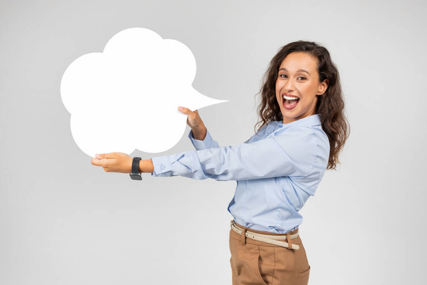 Shocked glad european woman in formal wear with open mouth hold abstract cloud for words and thoughts, text, isolated on gray studio background. Surprise, sale, good news - Photo, Image