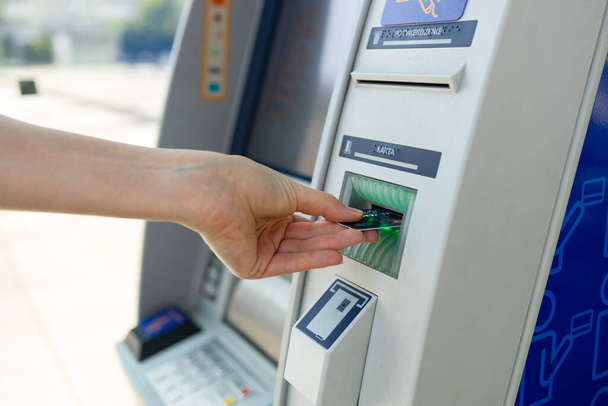 Mujer joven usando tarjeta de crédito y cajero automático mientras retira dinero. Foto de alta calidad - Foto, Imagen
