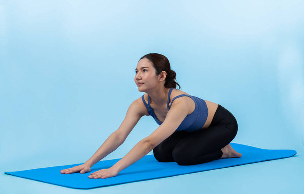 Mulher asiática em sportswear fazendo exercício de ioga no tapete de fitness como sua rotina de treinamento de treino. Cuidados corporais saudáveis e meditação calma no estilo de vida de ioga em corpo inteiro filmado em fundo isolado. Vigoroso. - Foto, Imagem