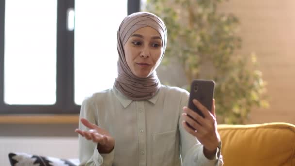 Remote work concept. Jonge professionele islamitische vrouw hr manager uitvoeren van online interview met de aanvrager, video chatten via smartphone op kantoor, tracking shot, slow motion - Video