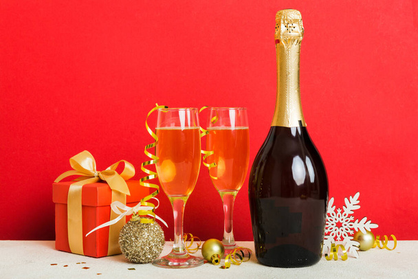 Champagne bottle with confetti, glasses and christmas decor on colored holiday background. Flat lay New Year decorations. - Foto, immagini