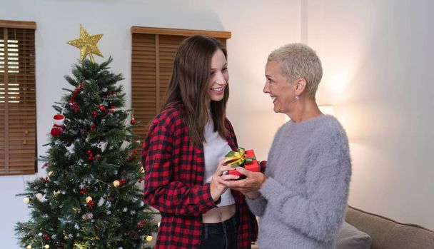 Boldog karácsonyt nyugdíjas nő és legidősebb lánya Cseréljen ajándékot Jó szórakozást ölelés egymást boldogan a karácsonyi ünnepek alatt.. - Fotó, kép