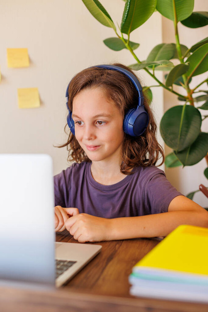 child listens to music at the lesson. Boy with curly hair is happy with distance learning. Lessons take place over the Internet. - Photo, Image