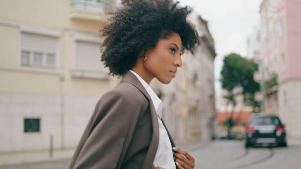 Magabiztos, göndör üzletasszony sétál a City Streeten, siet az üzleti találkozóra. Vonzó afro-amerikai nő átkelni az úton, gyönyörű város elegáns öltönyben. Komoly lány egyedül megy.. - Fotó, kép