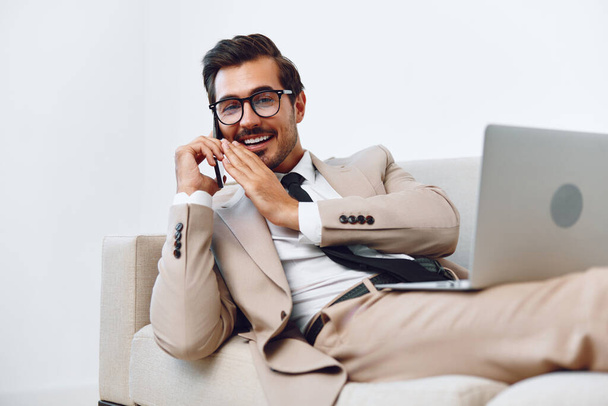 Attraente uomo caucasico video imprenditore manager occupazione adulto lavoro laptop vincente beige vestito ufficio telefono sorriso uomo d'affari divano chiamata lavoro parlare computer - Foto, immagini