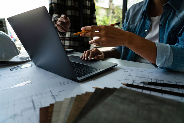 Twee ingenieur werken aan laptop te bespreken en brainstormen over bouwproject in kantoor. - Foto, afbeelding