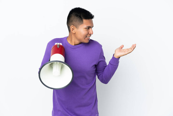 Young Ecuadorian man isolated on white background holding a megaphone and with surprise facial expression - Photo, Image
