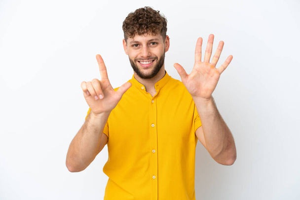 Nuori komea valkoihoinen mies eristetty valkoisella taustalla laskenta seitsemän sormilla - Valokuva, kuva