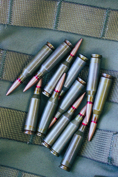 tas de munitions vivantes sur le tissu militaire tactique avec des ceintures filetées  - Photo, image