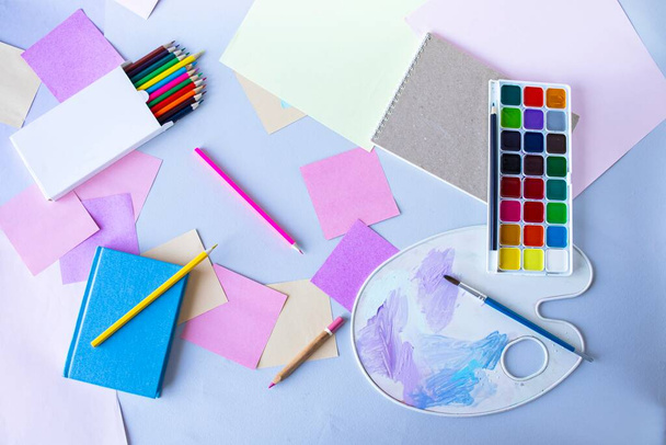 Voltar para a escola, tintas aquarela, pincéis e lápis de cor, paleta, material escolar em um fundo cinza, vista superior  - Foto, Imagem