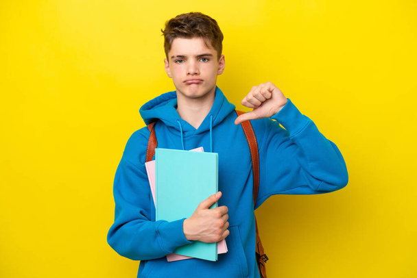 Teenager Russian student man isolated on yellow background showing thumb down with negative expression - Foto, immagini