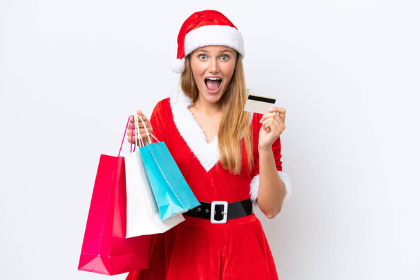 Anne Noel gibi giyinmiş beyaz bir kadın beyaz arka planda izole edilmiş, elinde alışveriş torbaları ve şaşırmış. - Fotoğraf, Görsel