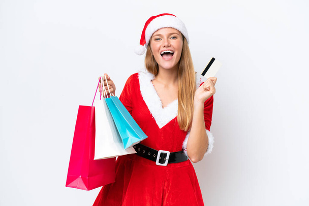 Anne Noel gibi giyinmiş beyaz bir kadın beyaz arka planda izole edilmiş. Elinde alışveriş çantaları ve bir kredi kartı var. - Fotoğraf, Görsel