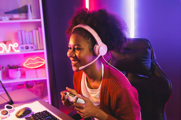 Host csatorna játék streamer, afrikai lány nyerő Esport képzett csapatjátékos és nézők online játék neon színes világítás szoba. Fogalom a cybersport beltéri tevékenységek. Kóstoló. - Fotó, kép