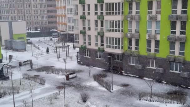 paisaje invernal, fuertes nevadas en la ciudad, vista de la ventana desde un nuevo edificio de apartamentos moderno al aire libre, primera nieve en la ciudad  - Imágenes, Vídeo