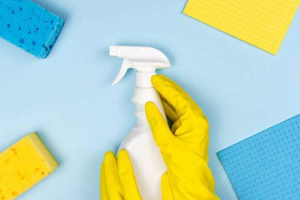 A woman's hands in a rubber yellow glove hold a spray cleaner. Cleaning concept. Top view. - Photo, Image