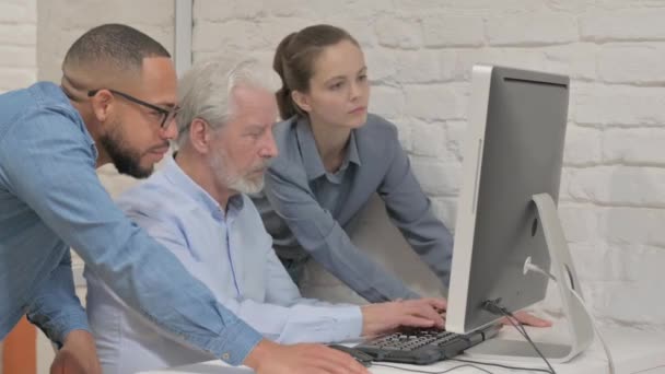 Personas de raza mixta mirando la cámara mientras trabajan en la computadora - Metraje, vídeo