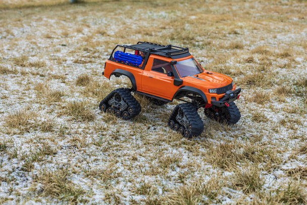 Widok z bliska pomarańczowy radiowo sterowany zabawka off-road pojazdu z gąsienicowych kół. Szwecja. - Zdjęcie, obraz