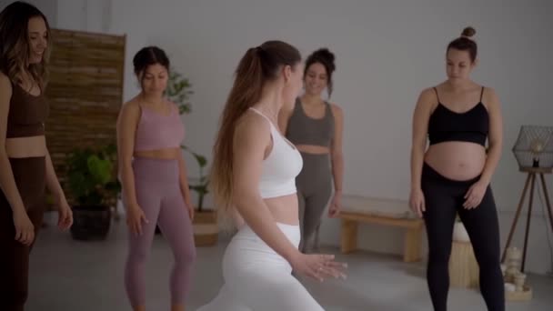 Diverse group of girls smiling happily in sportswear attending classes taught by yoga teacher. Cheerful friends exercising together in a gym. Sisterhood of women.  - Footage, Video
