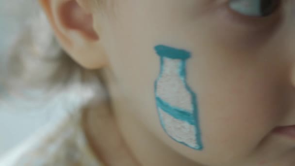 Milk bottle drawing on the face of a cute little girl. Agriculture concept. Macro. - Footage, Video