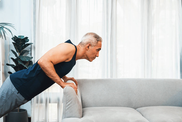 Спортсмен і активний старший чоловік, використовуючи меблі для ефективного націлювання на м'язи з підштовхуванням в домашніх умовах як концепцію здорового способу життя тіла після виходу на пенсію. Розрізати - Фото, зображення